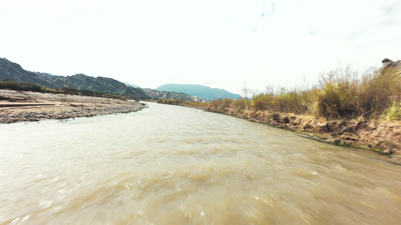 FPV drone image capturing the moment it flies under a bridge over a beautiful mountain river along Ruta 40 in the Salta region of Argentina