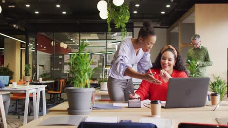 Happy-diverse-business-people-discussing-work-and-using-laptop-at-office