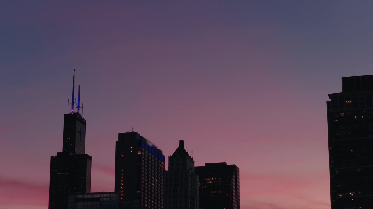 El horizonte de Chicago se recorta contra un colorido cielo al atardecer, destacando rascacielos icónicos. Ideal para proyectos de temática urbana o promociones de viajes.