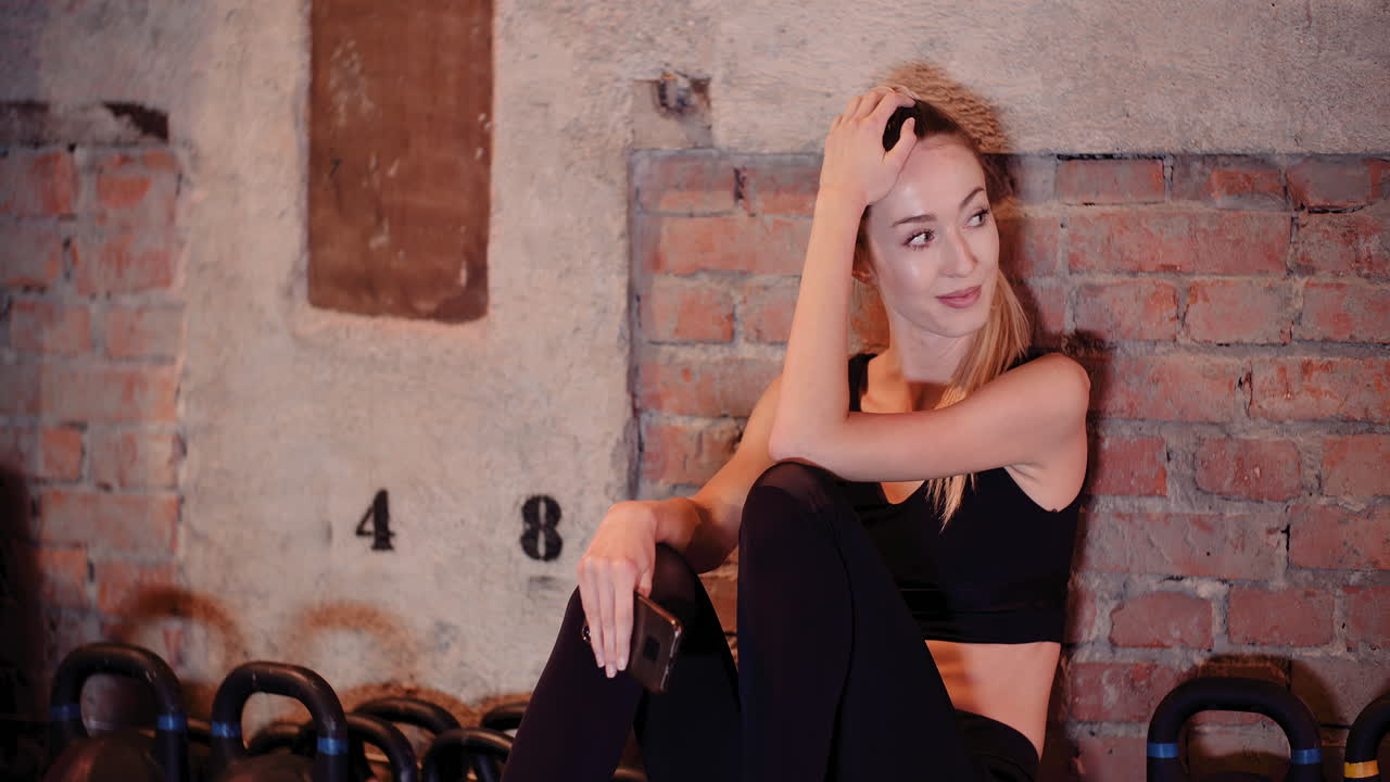 Bella atleta donna che messaggia con lo smartphone durante la pausa in un centro fitness 4
