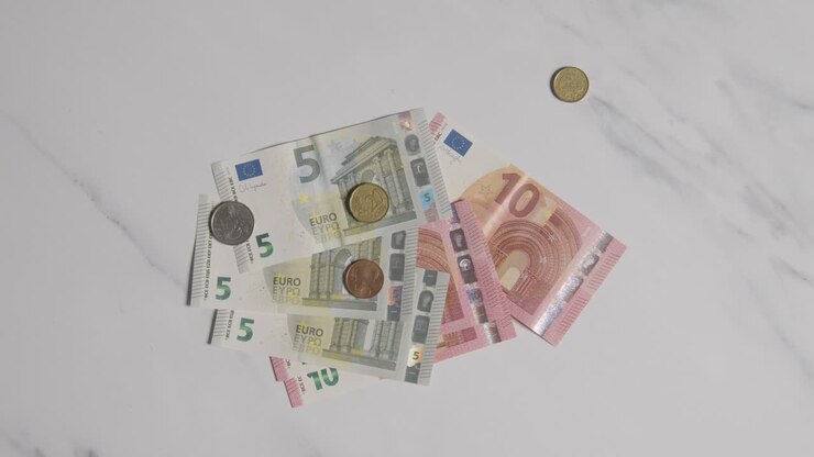 Plan en plongée de billets et pièces en euros étalés sur une surface en marbre