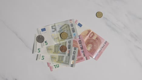 overhead-währungsaufnahme von euro-banknoten und -münzen, die auf der marmoroberfläche abgezählt sind