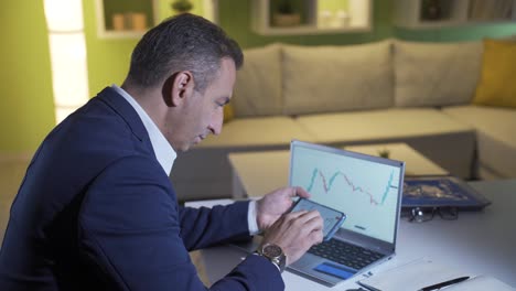 hombre siguiendo de cerca el mercado de valores y gráficos de criptomonedas en el teléfono.