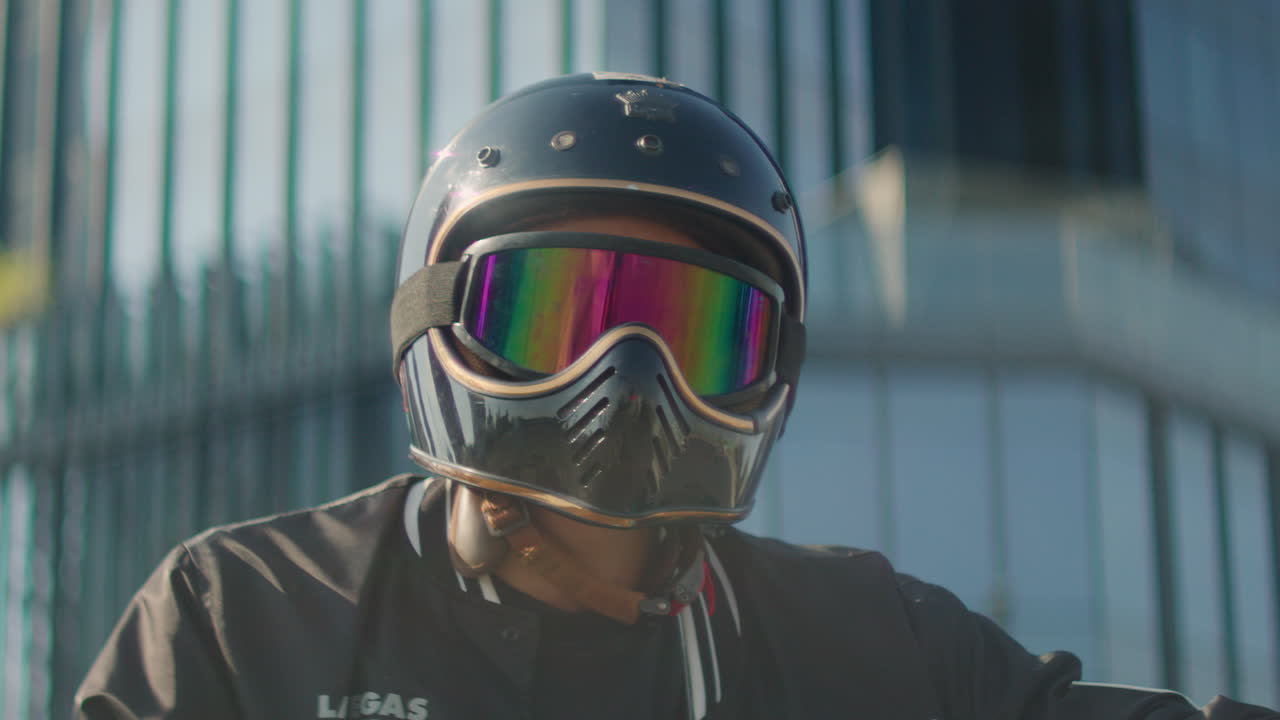 Person wearing a motorcycle helmet with rainbow goggles
