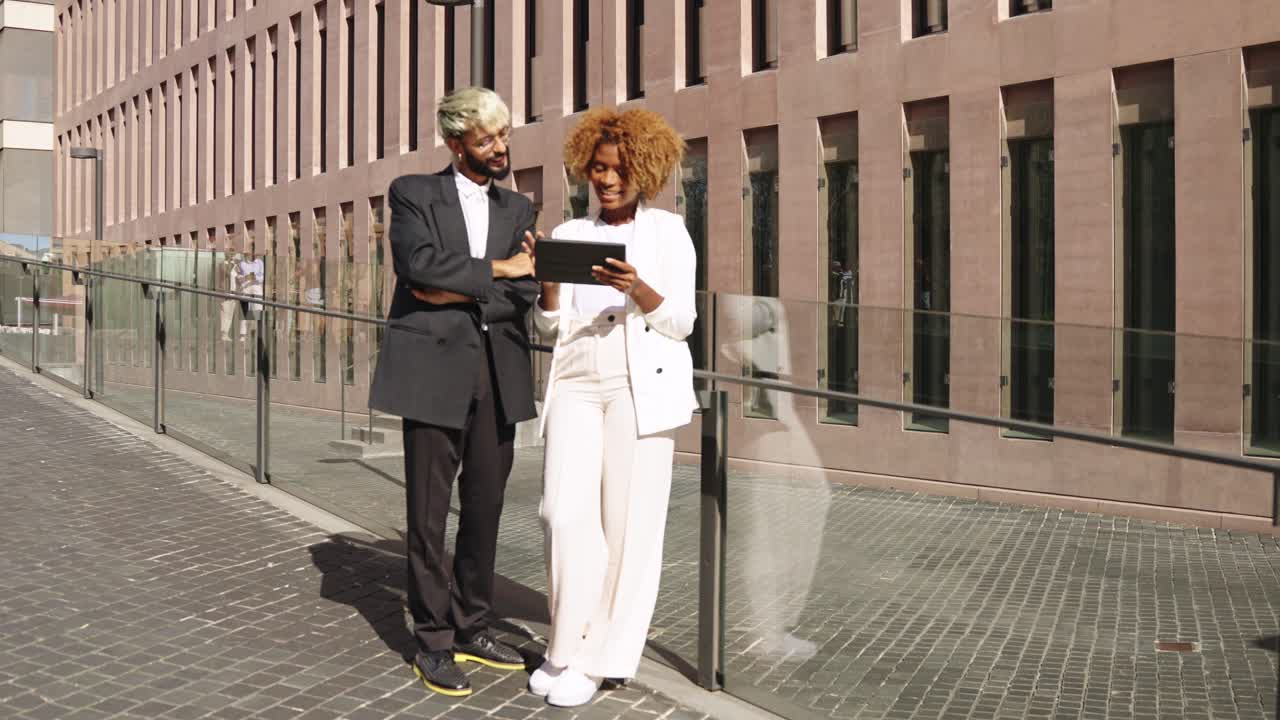 Two business people looking at a tablet on the street