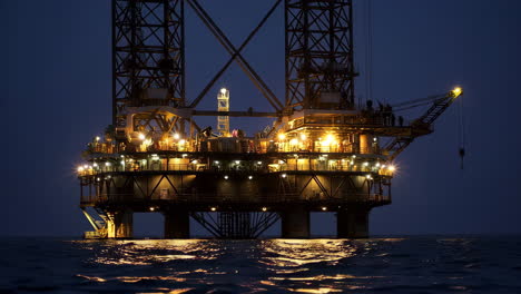 offshore oil rig at night with lights reflecting on water