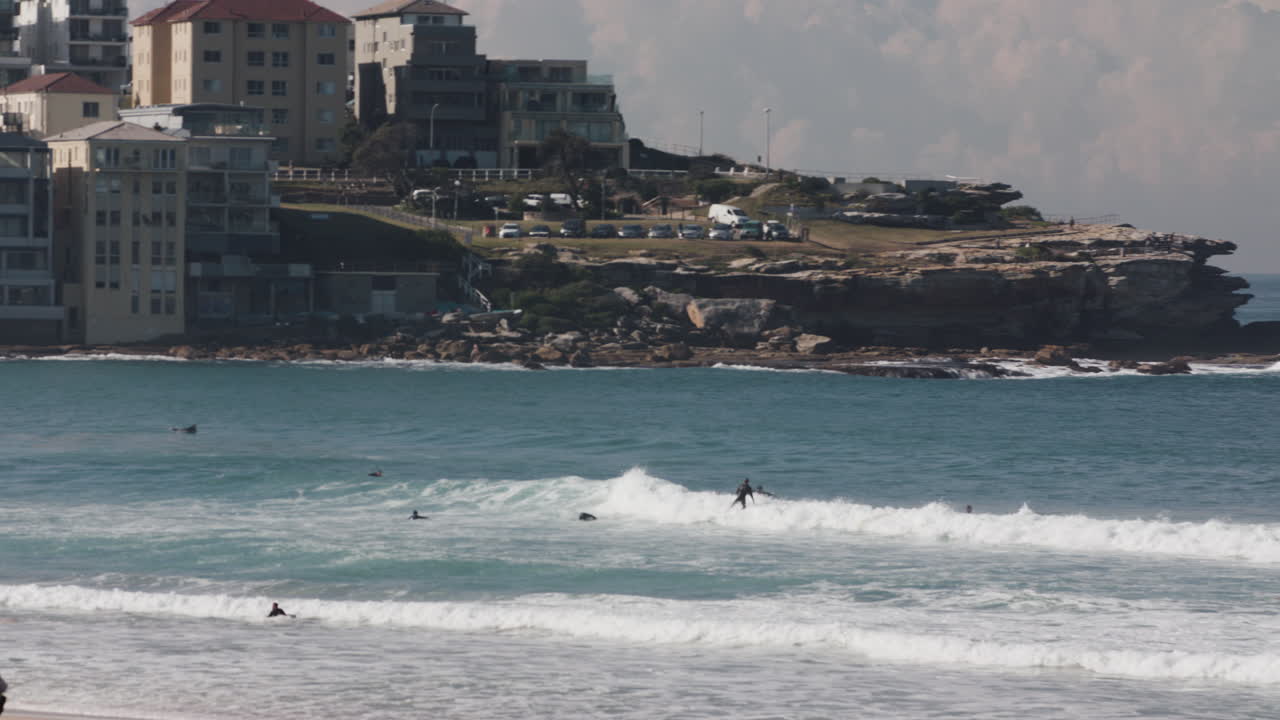 서퍼들은 화창한 날 시드니 근처의 호주 해안을 따라 파도를 타고 있습니다.