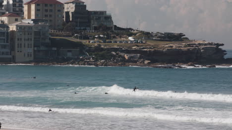 surfers ride in on a wave along the australian coast near sydney on a sunny day