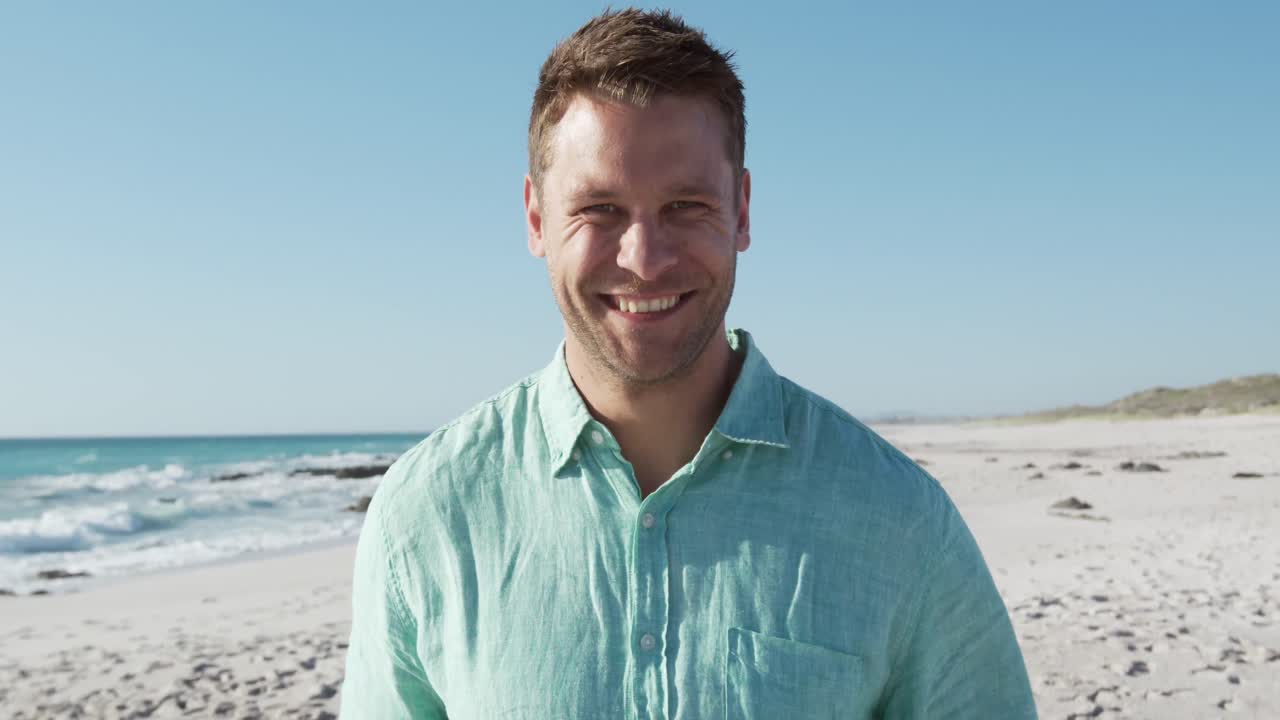 Mann står på stranden og ser inn i kamera