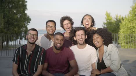 happy friends talking while sitting on bench in park