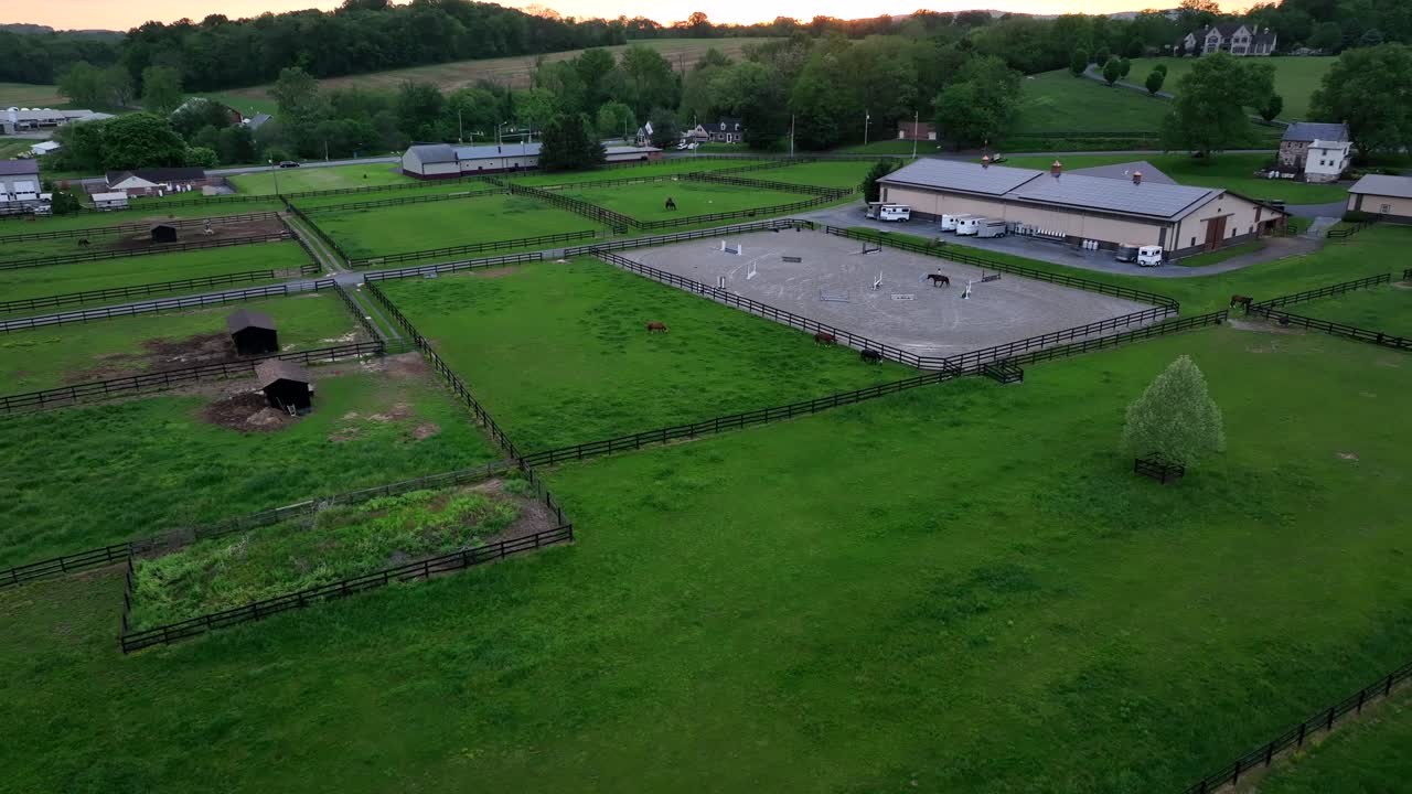 American farmers house with horses on field at horse farm. Aerial approaching shot. Rural landscape after sunset time in american suburb neighborhood. Wide shot,