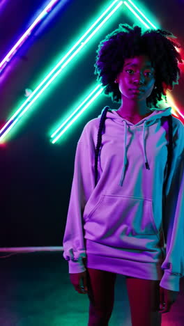 young woman with afro hair in hoodie under neon lights