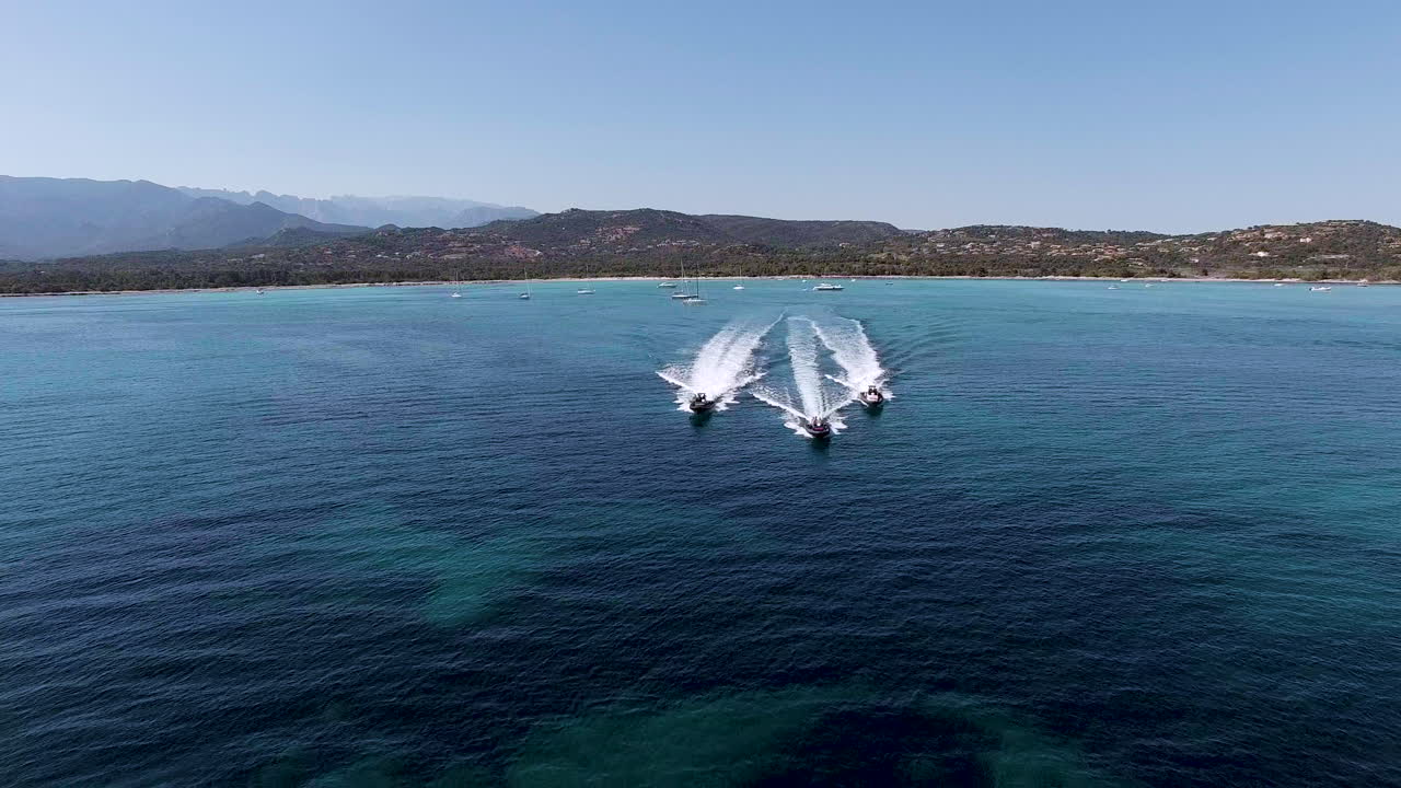 3 speedboats power across sea in formation, slow motion drone aerial shot in Corsica
