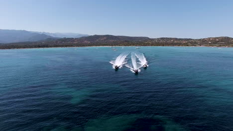 3 speedboats power across sea in formation, slow motion drone aerial shot in corsica