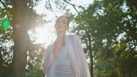 una chica romántica agitando las manos con una tela blanca frente a la brillante luz del sol de verano.