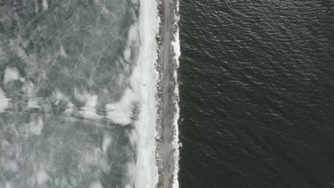 top down drone shot of a path, with ice on the one side and water on the other