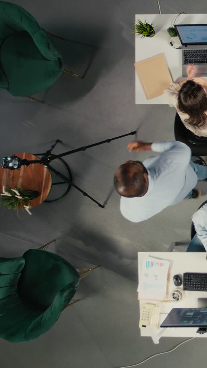 Vertikal video. Top-down view zoomer ud af et mangfoldigt personale, der optager en reklamefilm
