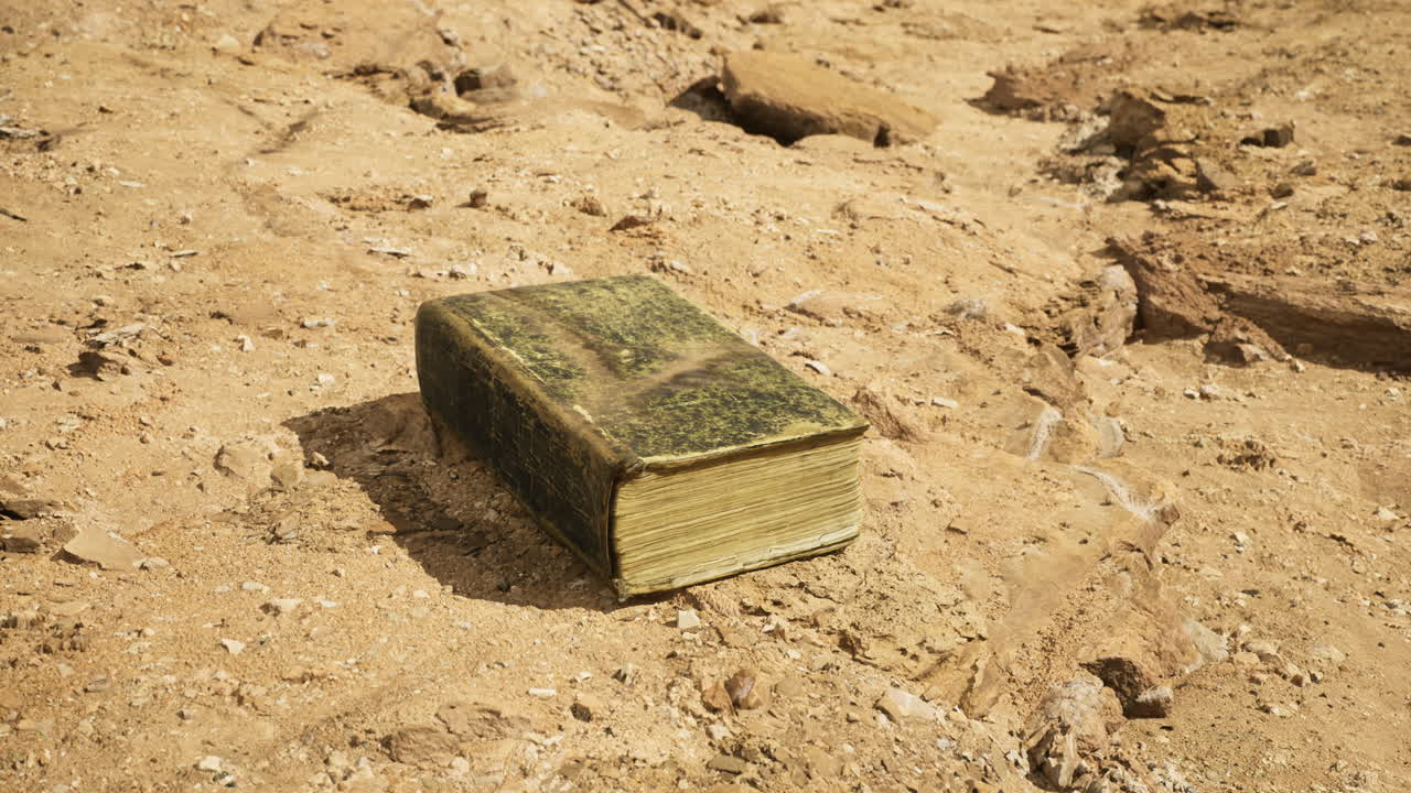 Antico libro appoggiato su terreno arido in un remoto paesaggio desertico