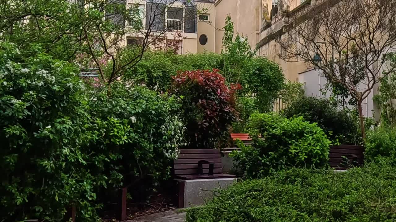 Explore a lush garden path leading to a historic building under a cloudy sky.