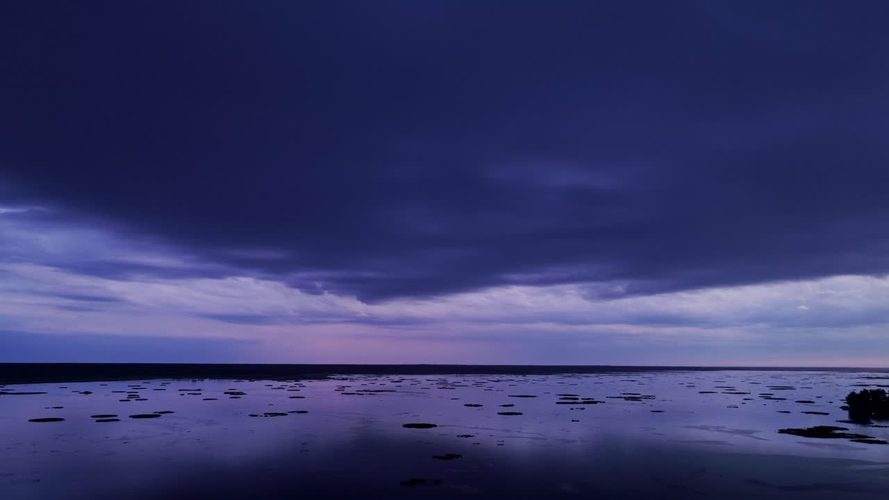 Letecký pohled na jezero za soumraku s tmavými bouřkovými mračny a fialovými odstíny vyplňujícími oblohu