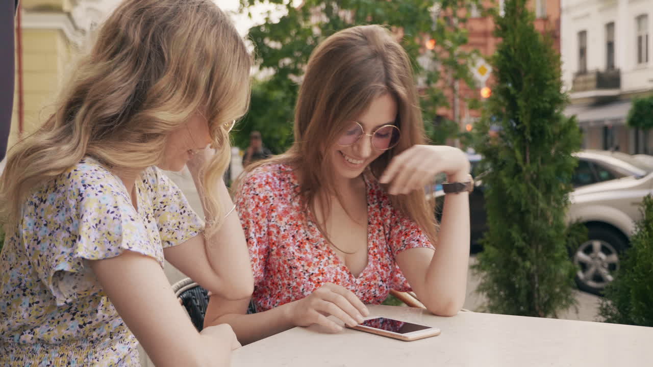 두 여자 친구가 야외 카페에서 즐거움을 즐기고 있습니다.