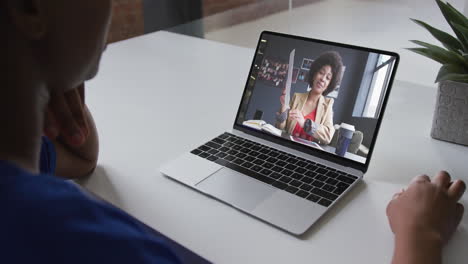 mid section of african american woman having a video call with female colleague on laptop at office