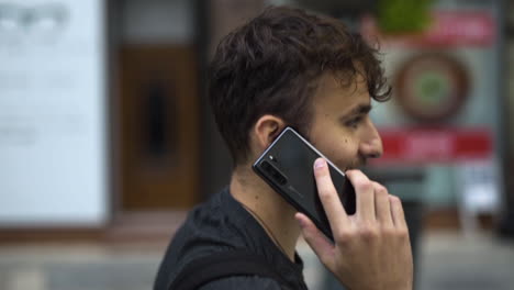 Man-walking-and-talking-on-phone-with-blurred-urban-background