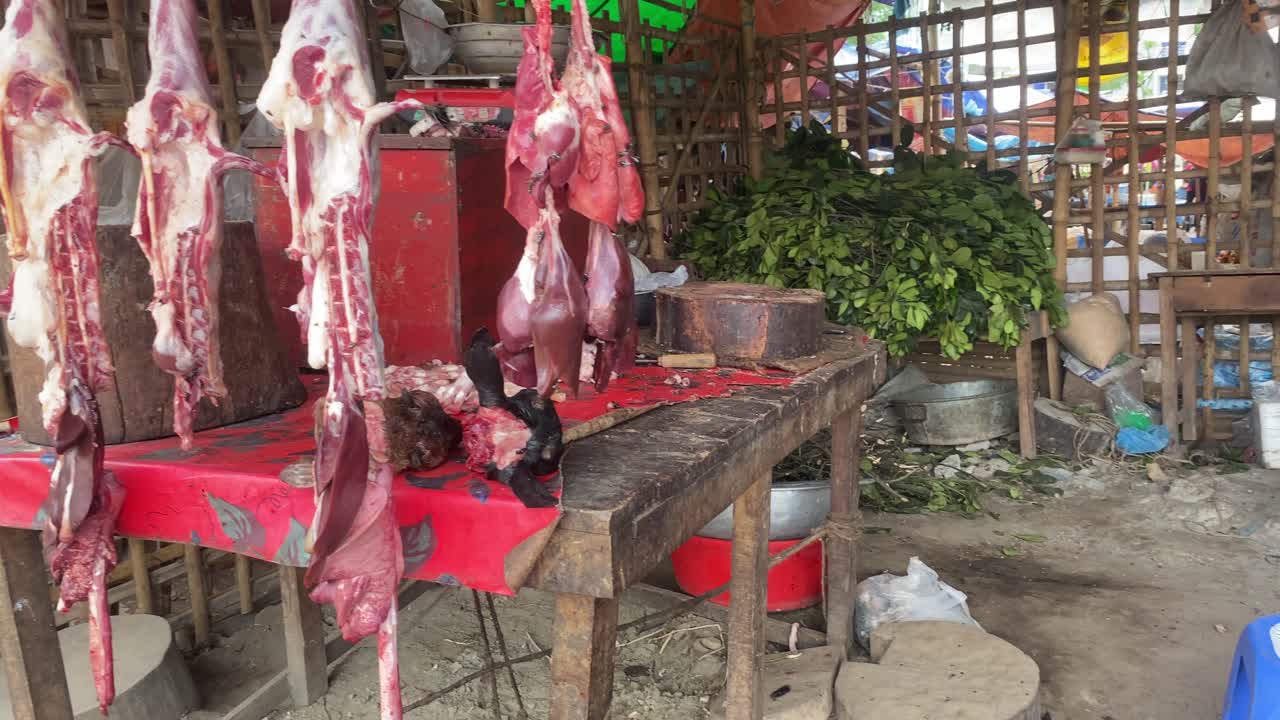 colgando carne de cabra cruda en los carniceros del mercado con
