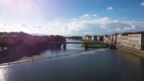 Vista-Aérea-Volando-Rápido-Sobre-El-Río-Arno-Y-La-Ciudad-En-Un-Día-Soleado-En-Florencia-En-Italia-En-4k