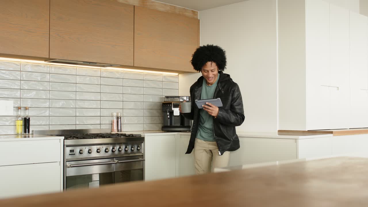 Uomo che scorre un tablet in cucina, vede una macchina da caffè, prende una tazza e sorseggia il caffè, spazio per il testo