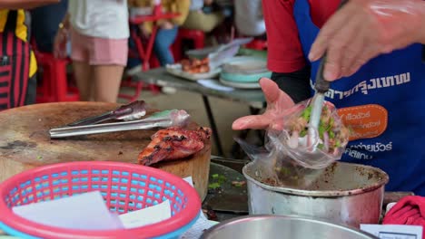 packing laab, a famous isan food originally from northeastern thailand, a mixture of minced meat and spices, served with grilled chicken sold at chatuchak weekend night market, bangkok, thailand