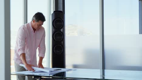 Front-view-of-Caucasian-Businessman-looking-at-blueprint-in-a-modern-office-4k