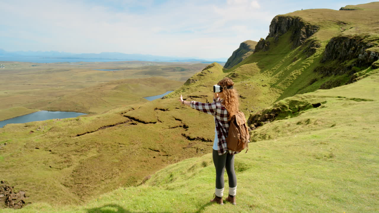vr 헤드을 착용한 여성이 스코틀랜드 하이랜드에서 하이킹을 하고 있습니다.