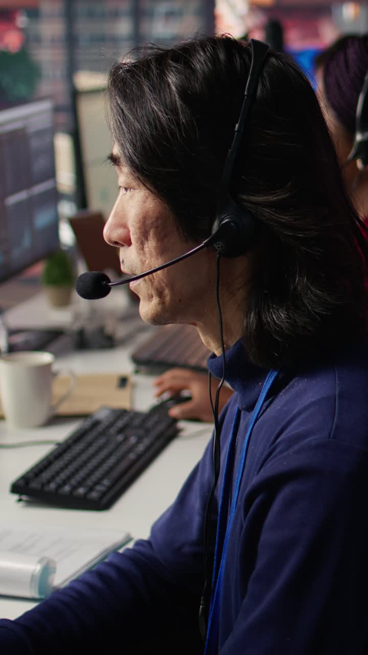 Vertical video IT support specialist in call center office doing troubleshooting, close up