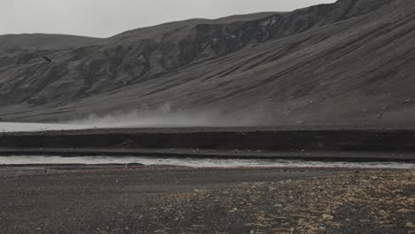 Dolly-shot-of-beach-with-steam-from-volcano-and-birds-in-the-sky