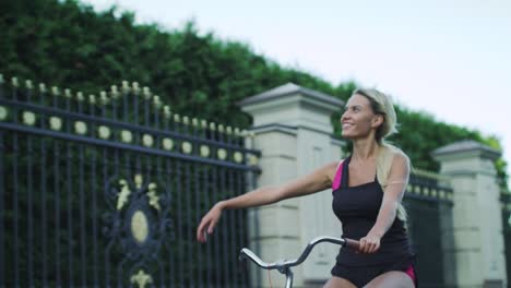 mujer feliz montando en bicicleta y agitando la mano en el parque. mujer disfrutando de la bicicleta