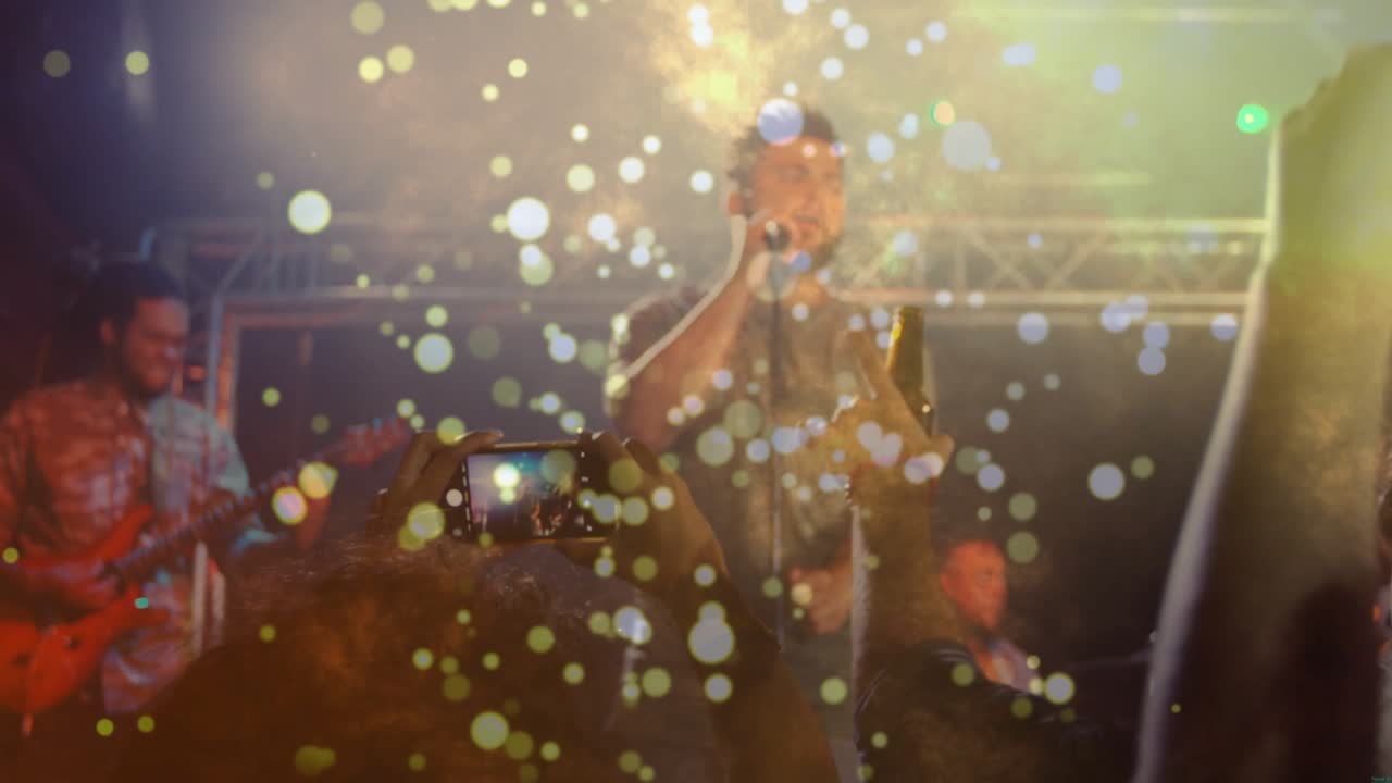 Fan che alza il telefono, folla entusiasta che registra mentre il cantante principale canta, con un bokeh sfocato che offusca i volti.