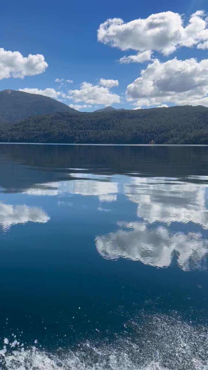 Clear reflection of clouds and mountains over Lago Lacar, Quila Quina, Argentina
