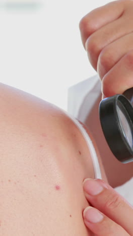 médico examinando al paciente con una lupa