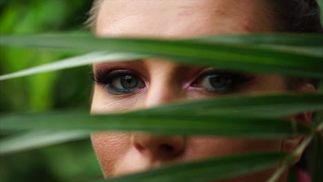 woman's face hidden by palm leaves