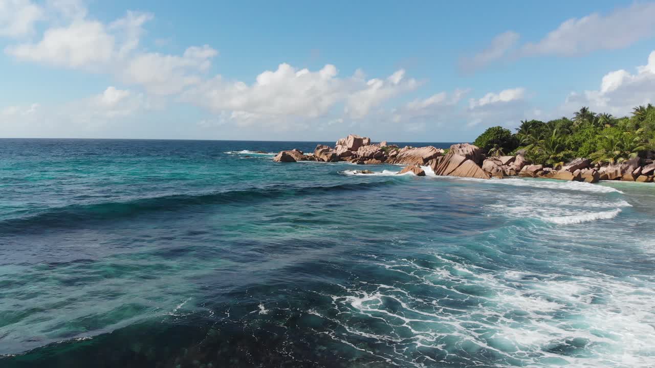 Vista aerea che segue le onde che si infrangono sulle spiagge bianche e deserte ad Anse Coco, Petit Anse e Grand Anse a La Digue, un'isola delle Seychelles.