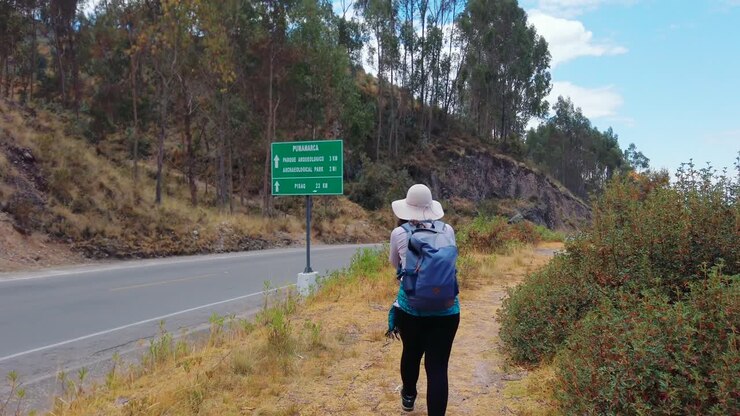 Donna escursionista cammina lungo un sentiero vicino alle rovine di Pukapukara a Cusco, Perù, esplorando le Ande