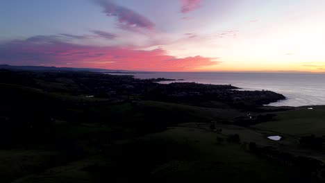 Drohnenansicht-Der-Landschaft-Aus-Der-Luft-Mit-Rosa-orangefarbener-Wolkenformation-Am-Himmel-über-Den-Vororten-Der-Ländlichen-Stadt-Kiama-An-Der-Küste-Der-Landzunge-Gerringong-An-Der-Südküste-Australiens,-Reisetourismus