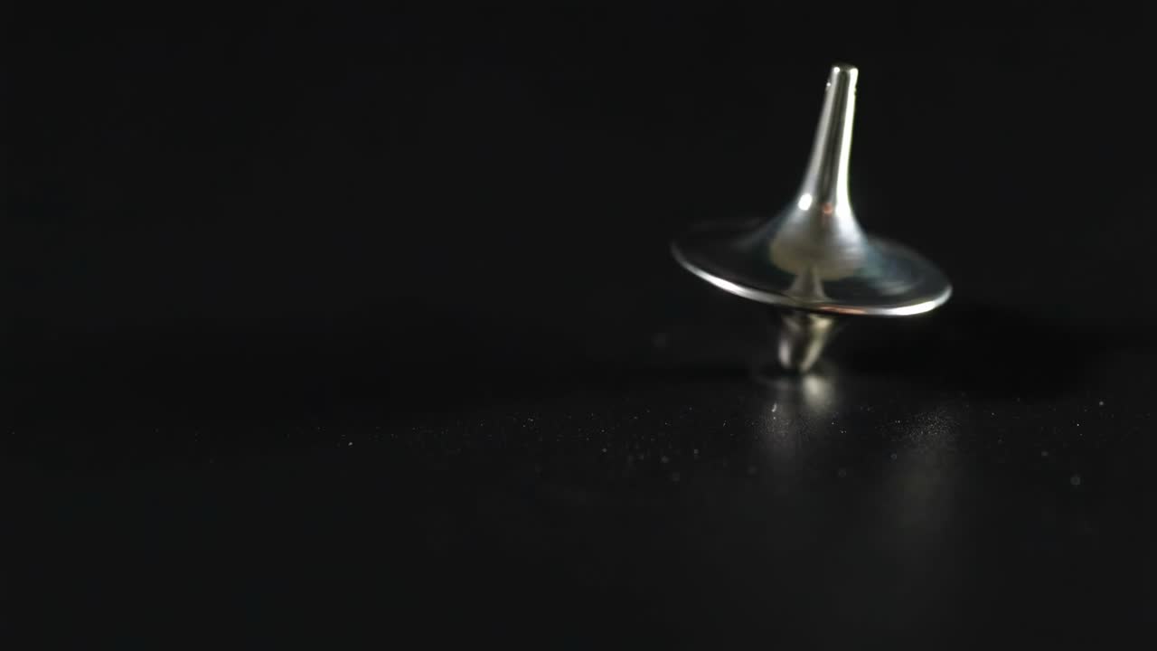 A metallic top spins smoothly on a dark surface, showcasing balance and motion.