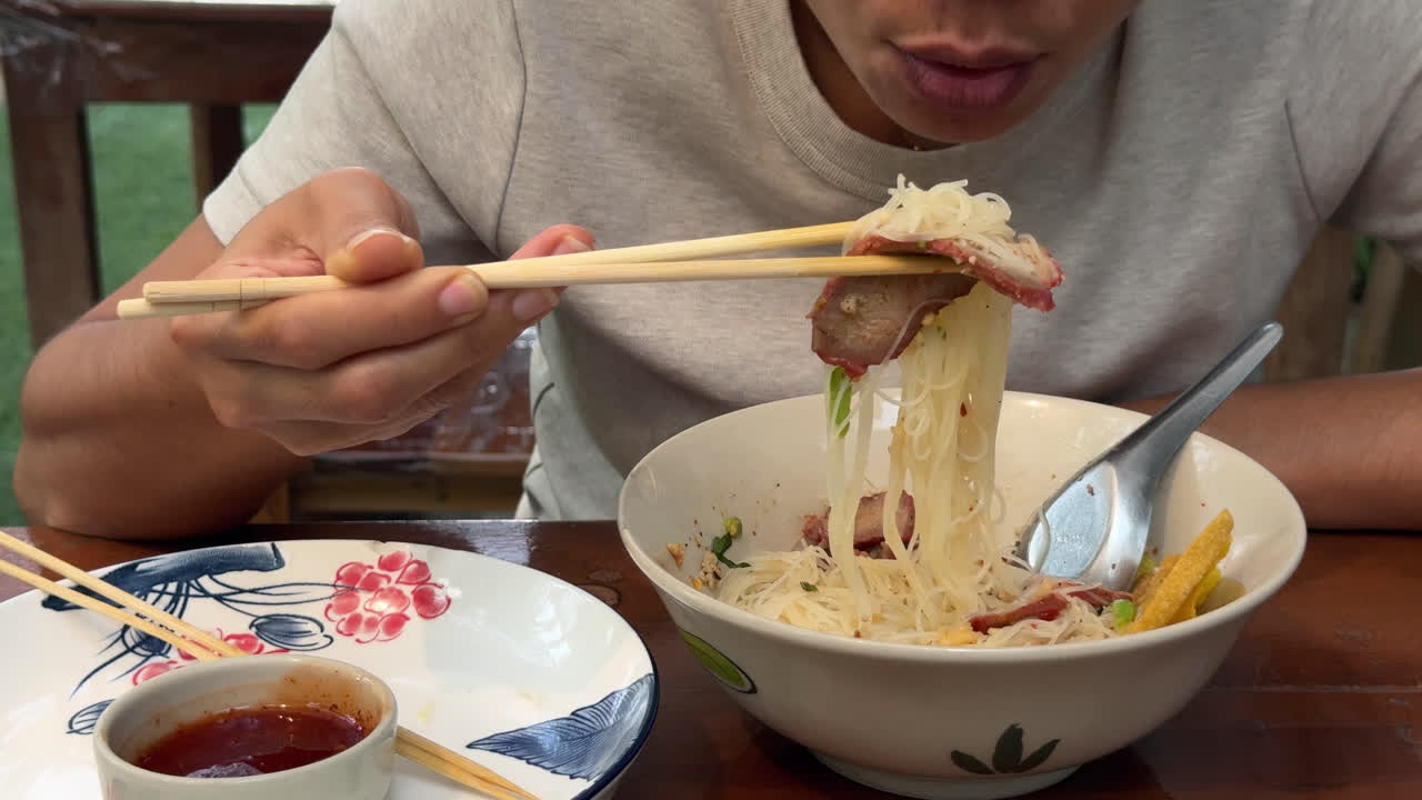 Eating Boat Noodles At Thai Restaurant Using Chopsticks. closeup shot