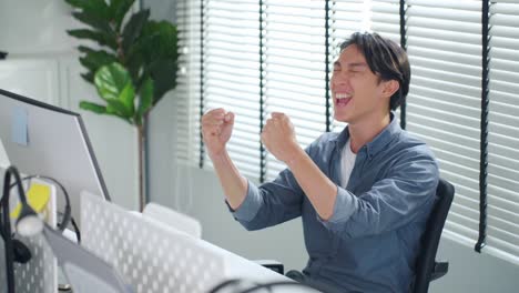 happy man celebrating success at computer desk