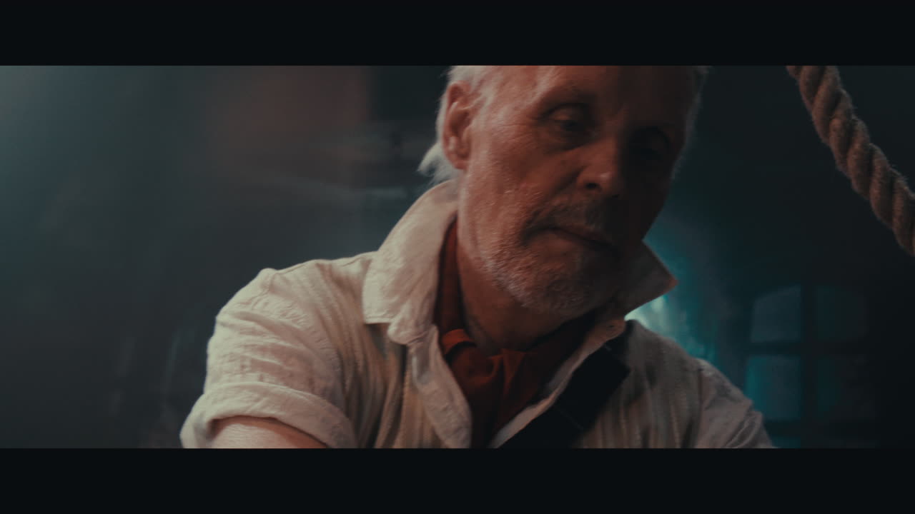 An old captain sits writes a letter inside the sailing ship cabin