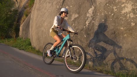 sporty cyclist woman wearing helmet in a road during sunset