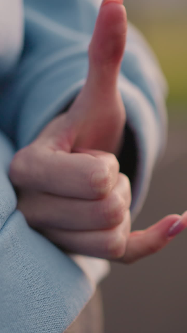 화려한 손을 가진 여성이 허리에 가까이 올려져 손의 몸짓을 하고, 흐릿한 배경으로 부드러운 조명이 그녀의 시안 스웨터와 운동 중에 운동적인 자세를 강조합니다.