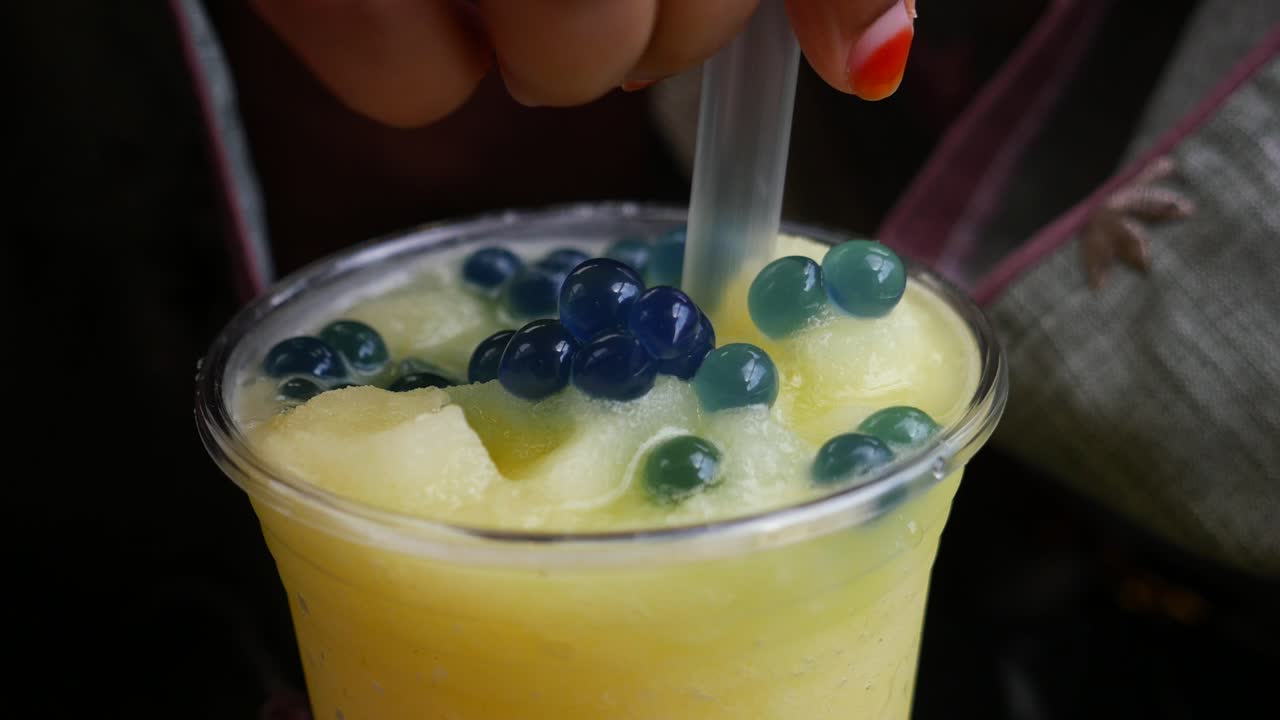 파란색 보바 진주와 함께 노란색 음료의 클로즈업